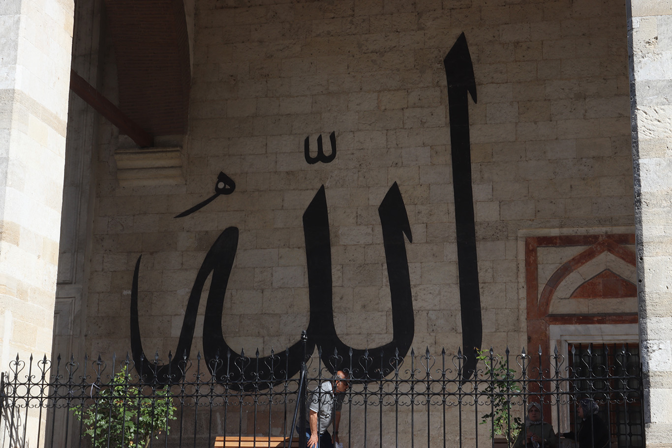 A beige brick wall with the arabic inscription of Allah.